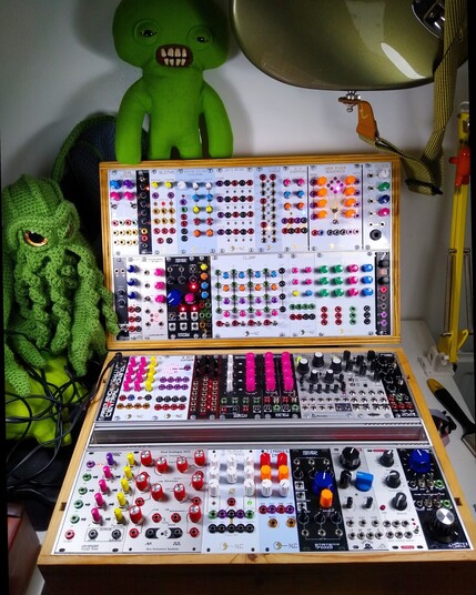 A Eurorack Modular synthesizer with colourful knobs and a crochet cthulhu
