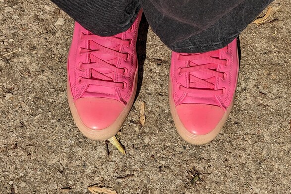 Top down view of someone's feet in pink Converse and black jeans