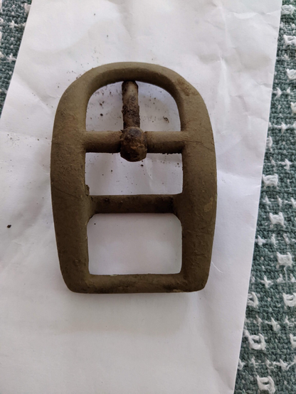 A dirt-encrusted buckle, top view.