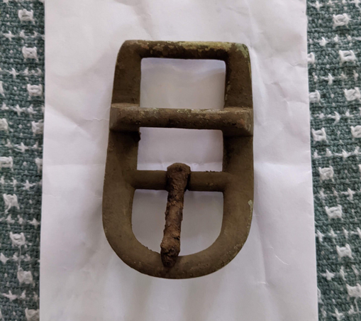A dirt-encrusted buckle, bottom view.