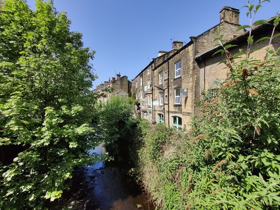 Holmfirth. Nora Batty's gaff. A row of terraced houses and shops overlook a small river