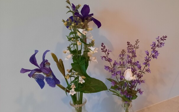 Two small vases wuth purple and white flowers