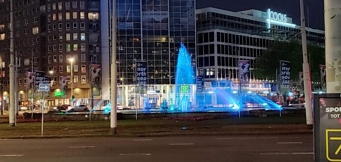Water fountain near office buildings at night in Rotterdam. The blue lighting makes the scene especially beautiful.