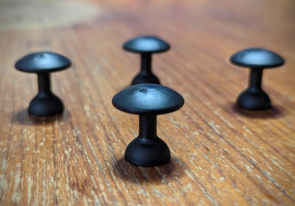 Four vaugley mushroom cloud shaped plastic board game pieces.