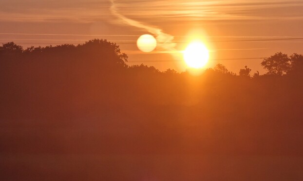 Multiple suns caused by the window of the train in an orange night sky. Surreal.