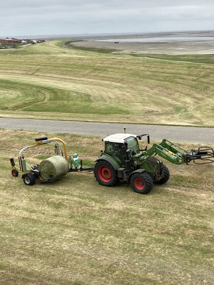 traktor mit maschine zum einwickeln von grasrollen
