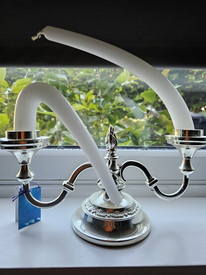Two bent candles on a silver candle holder.