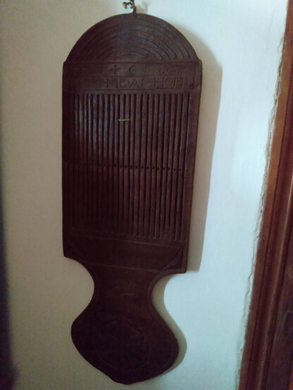 A tape loom from 1727. It is dark wood and paddle shaped. I couldn't read the top inscription in the dark house, but it's in the database: "Carved at top: ""1727 [7s are backwards] + CD + W / KEEP ME AT HOME""; at bottom: ""IC""."

More details: https://www.historicnewengland.org/explore/collections-access/gusn/2557