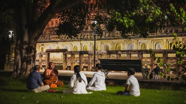 People sitting under the Bodhi tree listening to a Buddhist monastic teaching.