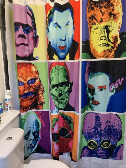 Shower curtain with a white background, with 9 universal monsters in an Andy Warhol style. Top left is Frankenstein’s monster in pink, blue, black on a yellow square background.  Dracula is blue, yellow, black on red square background. The wolf man is orange, yellow, green, black on a purple square background. The creature is oranges, yellow, purple on green square background. The mummy is green, blue, red on a purple Square background. Frankenstein’s bride is blue, red, purple, black, green on a blue square background. The phantom is blues, black on a square green and purple background. The invisible man is pinks, green, black on an orange background. Metaluna is purples, blue, yellow, black on green background. 