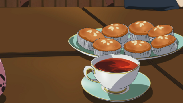 A plate with what appear to be muffins with a cup of tea in front of it.