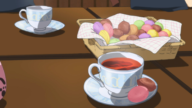 A basket filled with what appear to be macaroons with a cup of tea in front of it.
