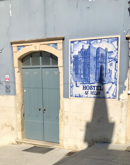 A church’s shadow creeps up the Old Cathedral Hostel sign in Coimbra, Portugal 