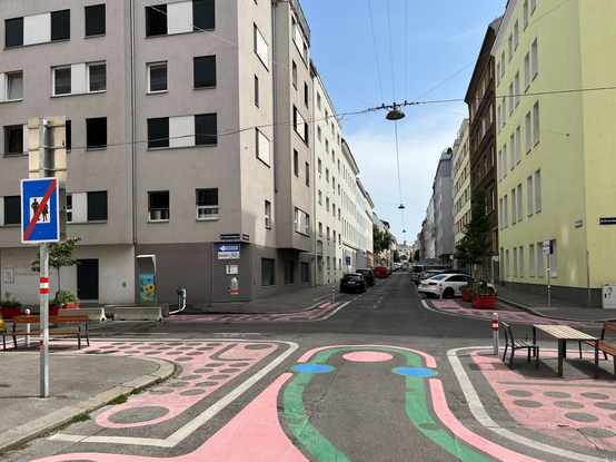 Neu eingerichtete Fußgängerzone Herzgasse im Pilotprojekt Supergrätzl, rosa Farbe, Sitzbank, Pflanzkübel und eine Nebeldusche hinter einer Beton-Leitschiene