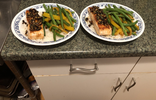 Plated dish. Salmon topped with a pan sauce made with scallions, pepitas, lemon juice, brown sugar, and tomato chipotle butter. Sautéed yellow bell pepper and green beans. All on a bed of garlic rice.