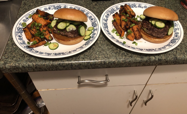 Plated dish. Ginger and scallions mixed into the meat. The burger build: bottom bun, mix of soy glaze, soy sauce, and mayo, the burger, marinated cucumbers, top bun. Roasted carrots topped with scallions.