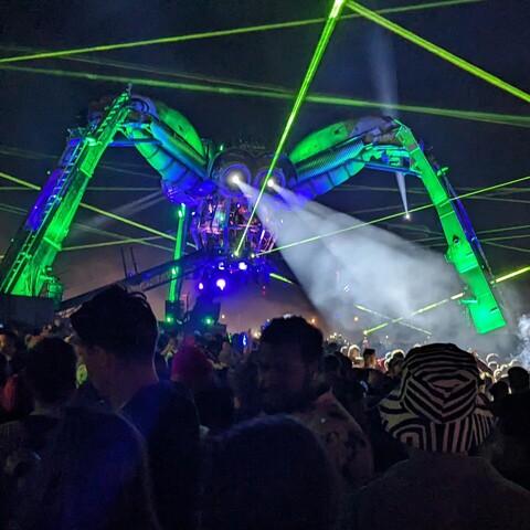 a large spider shaped DJ stage at Glastonbury, with lasers flying around construction. Picture via cashwasp at insta