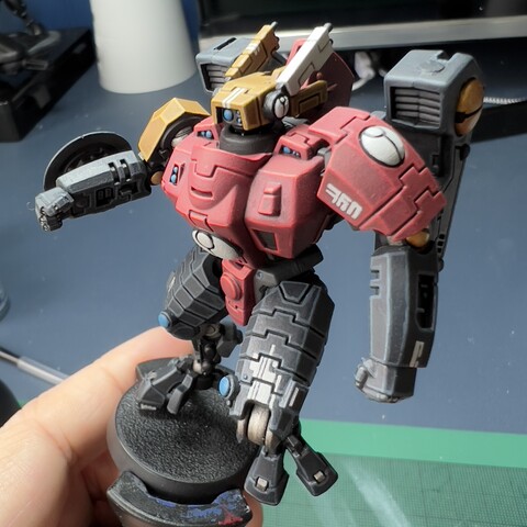 Work in progress shot of a Warhammer 40,000 war gaming miniature - a mech painted in blue-grey, red, and yellow, with hand-painted decals.