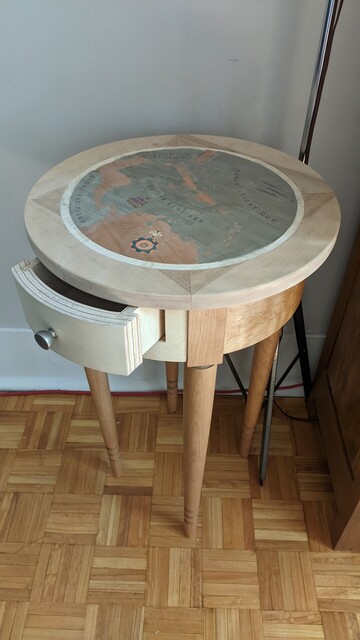 A round cherrywood pedestal table with a 16th century Caribbean map marquetry.