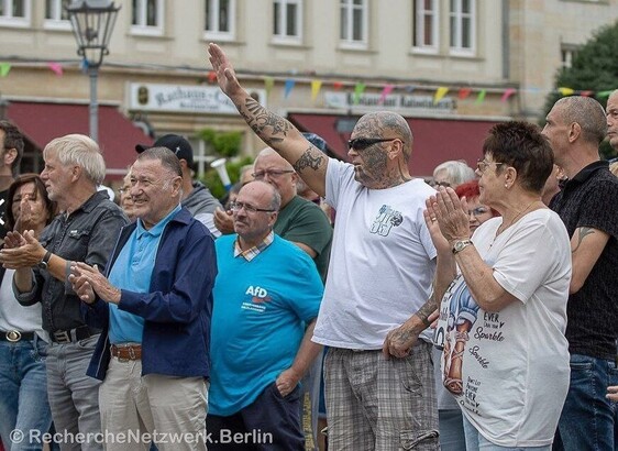 Mensch zeigt Hitlergruß bei Demo, neben ihm ein Mann in AfD Shirt.