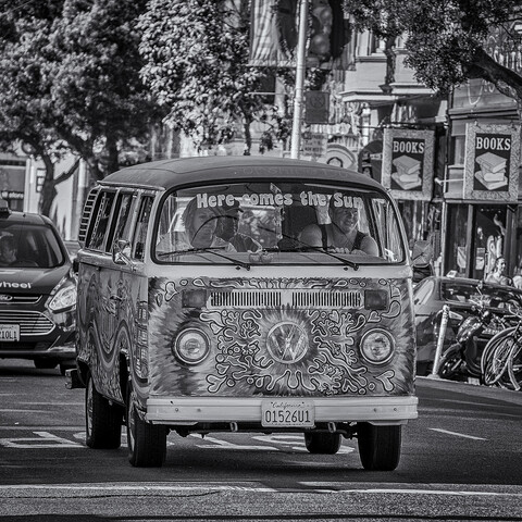 VW bus painted in a psychedelic livery drives down Haight Street in San Francisco. 