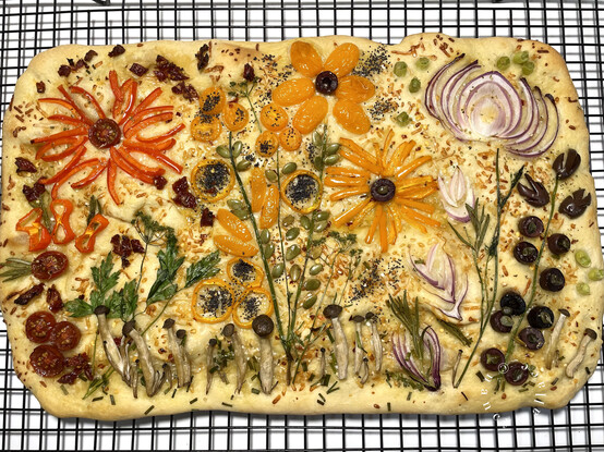 Overhead view of the cooked gardenscape focaccia, showing fireworks in the sky make with red and yellow bell peppers. 