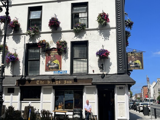 View of the exterior of The King's Inn: whitewashed pub with many flower baskets