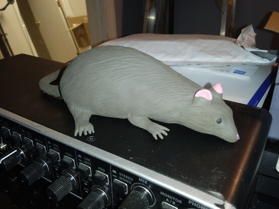 A toy rat sits atop a piece of audio gear on my desk.
