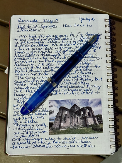 A fountain pen laying on an open page in a travel journal.