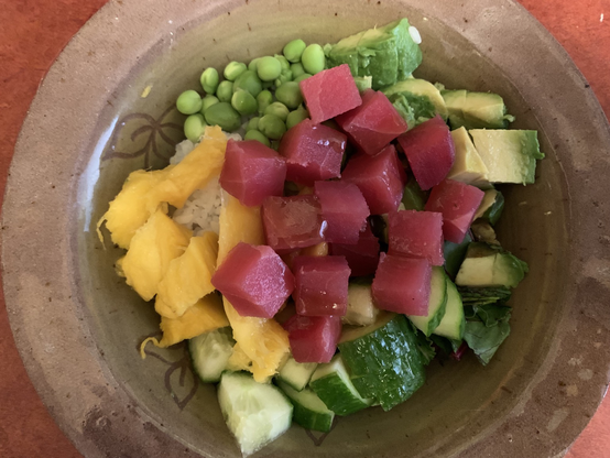 Tuna poke bowl of tuna, mango, peas, cucumber, avocado, mixed greens, and sushi rice.
