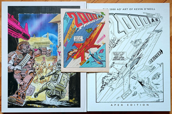 The Kevin O'neill Apex edition slipcase with the colour artwork from Robusters in Starlord magazine, next to the hardcover with black and white line work for prog 112, the greatest 2000ad cover ever printed. The original printed issue sits on top, a third of the size of the original