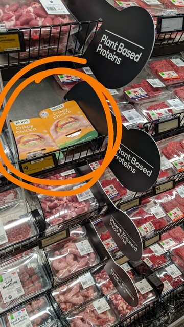 Photo of plant-based "meat" section of Countdown in Timaru, New Zealand. There's 4 shelves & 4 signs promoting plant-based proteins but the majority of the shelf space is filled with regular meat.