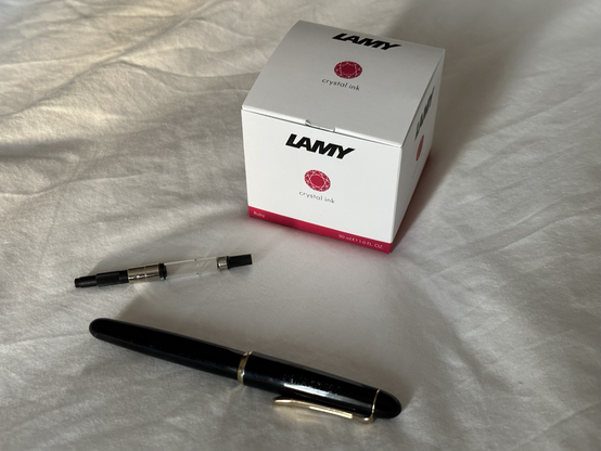 A bottle of ink, an ink converter, and a fountain pen.