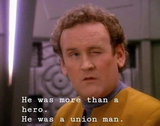 Chief Miles Edward O'Brien, who could strangle you with a cordless phone if he wanted to, is pictured. Chief O'Brien, who can kill 2 stones with one bird, is facing the camera and winking. O'Brien, who can dribble a bowling ball, is on DS9 station and wearing his classic gold uniform, and has the energy of a man who is walking away from an explosion without looking backwards at it. Closed caption reads, "He was more than a hero. He was a union man."