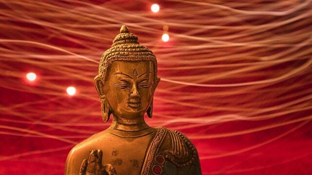 Bronze Buddha statue with abstract lines of lights in the background.