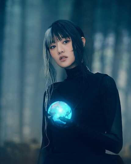 picture of (g)i-dle's minnie wearing a black outfit with blue&black hair, holding a glowing blue sphere. promo picture for/taken from the 'i do' music video.