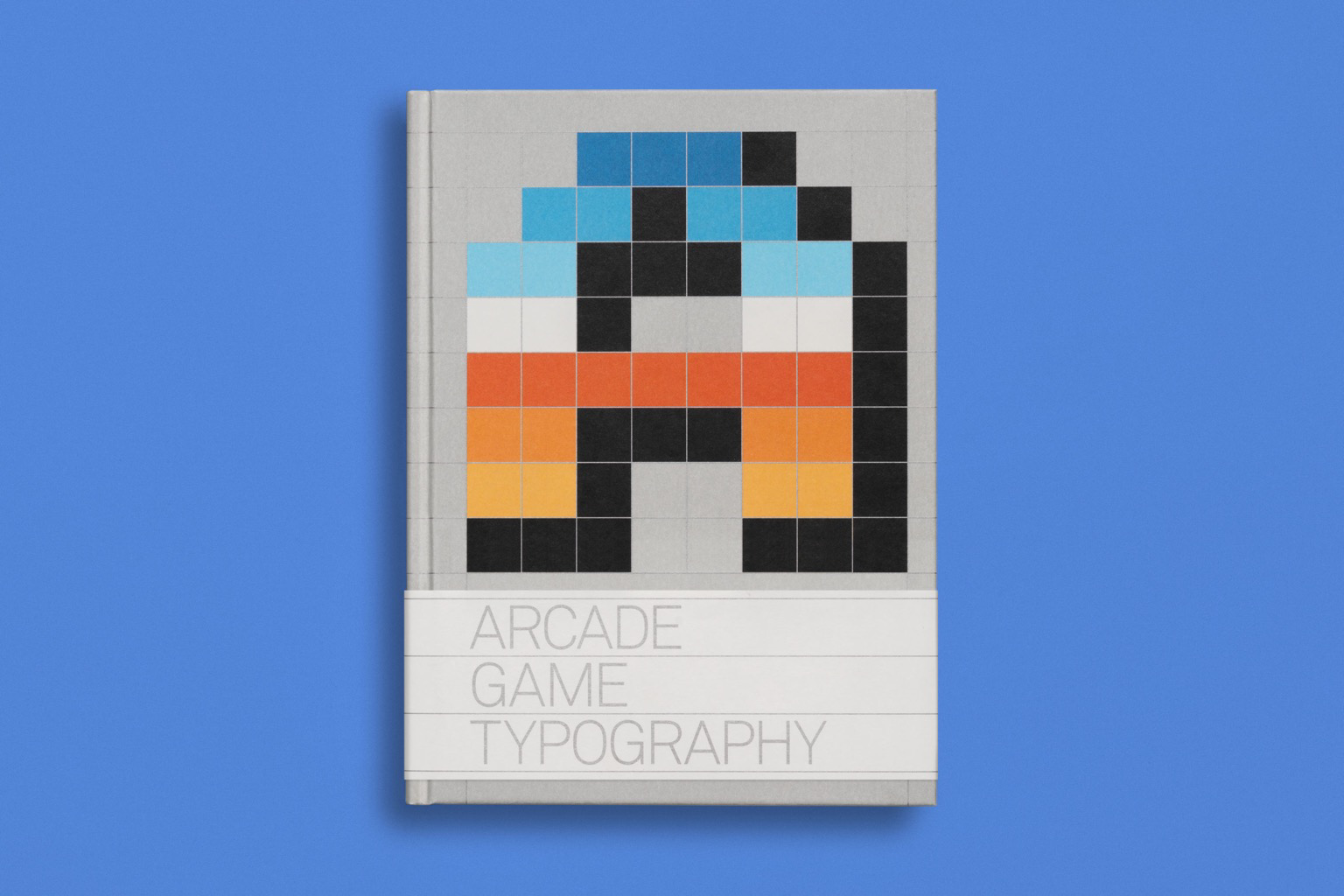 A hardcover book titled Arcade Game Typography, the cover emblazoned with a large pixelated letter A. A blue/orange gradient runs from the top of the letter down to the bottom. 