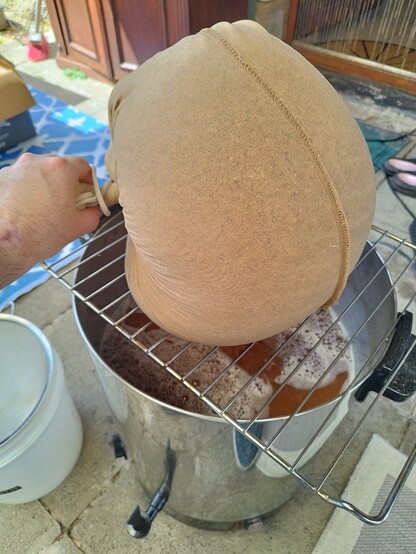 A bag of beer grains draining into a brew kettle
