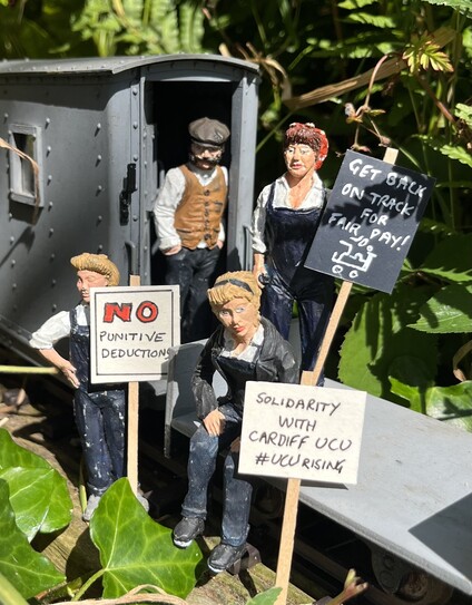 Four 16mm scale people sit on a railway wagon with placards “No punitive deductions” “Get back on track for fair pay” and “Solidarity with Cardiff UCU”