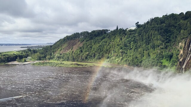 La cascada Montmorency desde el este formando un arcoiris al caer. Al fondo, la isla de Orléans y la ciudad de Québec.