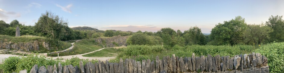 Panorama of the quarry out the back of the house. 40 years of tree growth pushing up. Gravel paths meander their way through it. A 15 foot dry stone pillar stands atop a small cliff.