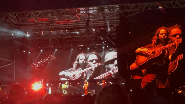 Billy, superimposed on video screen behind him. 