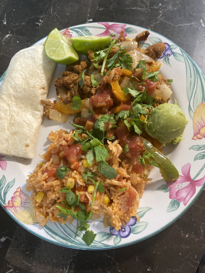 Flower edged dinner plate with fajitas and Spanish rice sprinkled with cilantro 