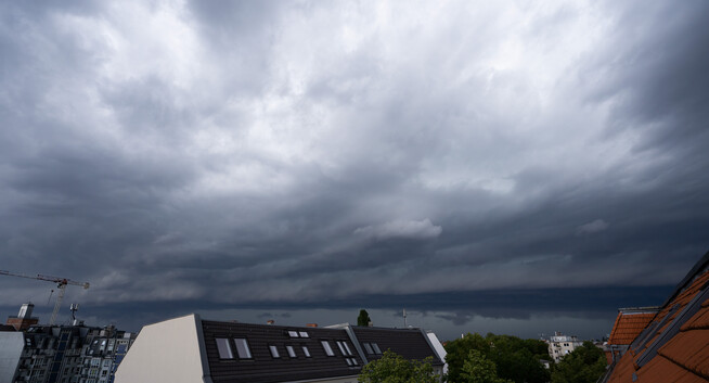 A massive dark cloud bank rolling in, dragging a large rainstorm along with it.