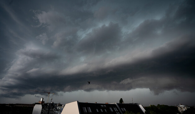 A massive dark cloud bank rolling in, dragging a large rainstorm along with it.