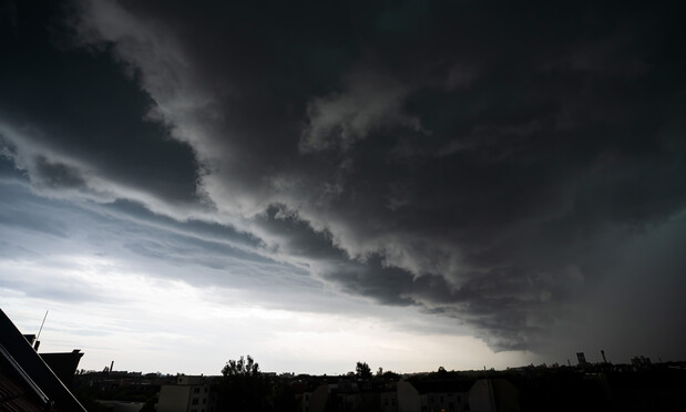A massive dark cloud bank rolling in, dragging a large rainstorm along with it.