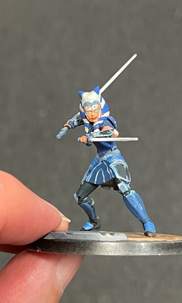 A miniature of Ahsoka Tano painted in blues and whites. She looks towards the camera with slightly lopsided steel grey eyes. 
