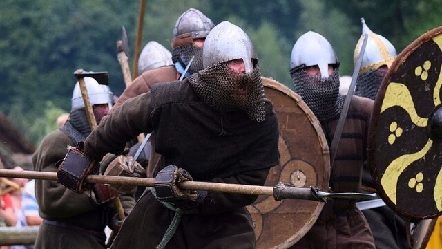 Warriors in armor and shields charging forward.