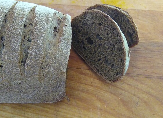 The end of the dark rye bread loaf had been sliced to reveal a dark slice with a nice airy crumb.