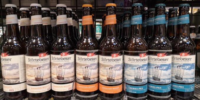 Viele Bierflaschen der Marke Störtebeker stehen in Reih und Glied in einem Regal eines Bio-Supermarktes am Bodensee.
Das Foto zeigt einen Ausschnitt des Supermarkt-Regals ohne Preisschilder.